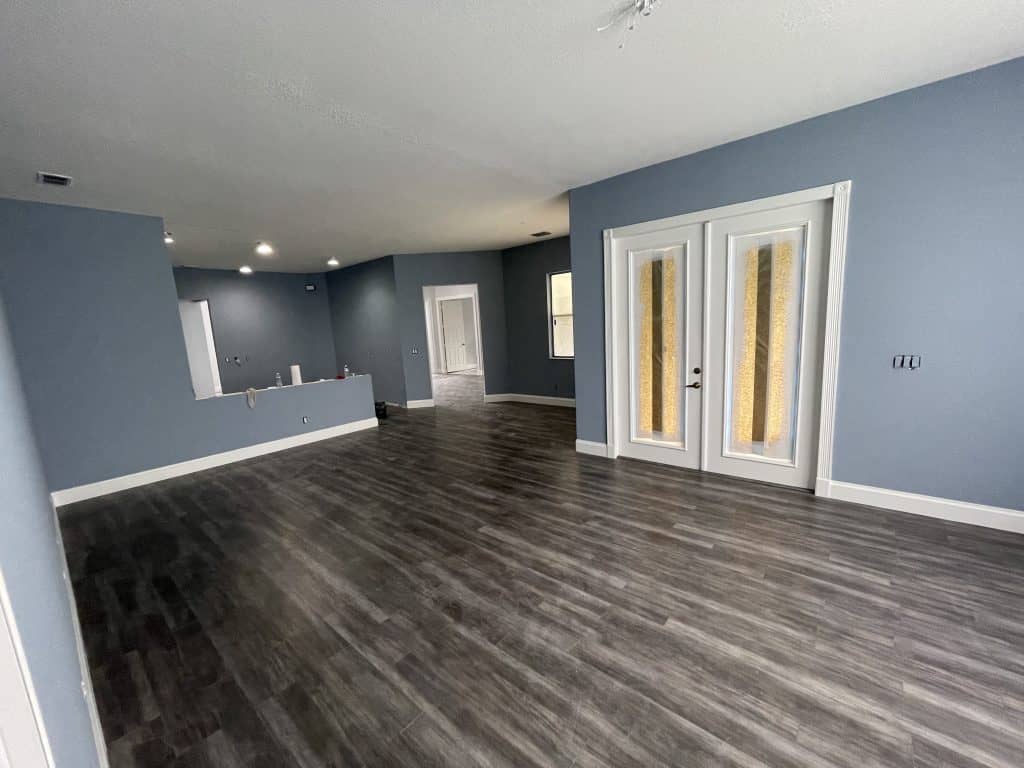 Empty living room with blue walls and hardwood floors.