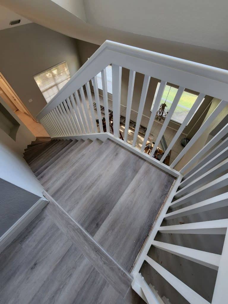 A stairway with wood flooring and a white railing.