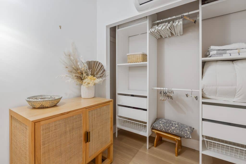 A closet in a room with white shelves and a fan.