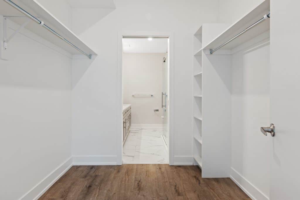 A white closet with a wooden floor.