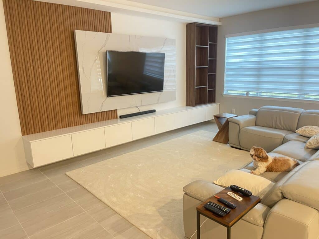 Modern living room with a wall-mounted television, minimalist furniture, and a dog sitting on the rug.